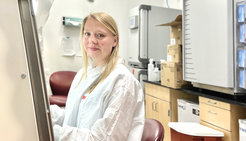 Franziska Sendker is standing in a lab coat in front of a lab bench.